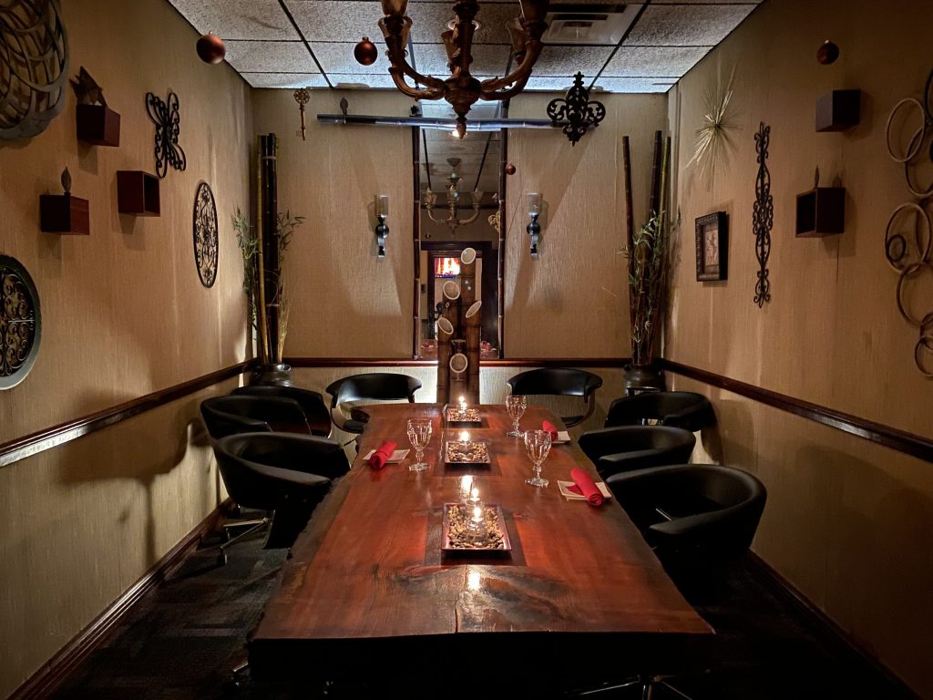 Cozy private dining room at The Orchards with a rustic wooden table, modern black chairs, wall art, and warm ambient lighting.