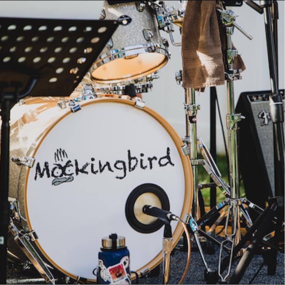 Close-up of a drum set with 'Mockingbird' logo on the bass drum.